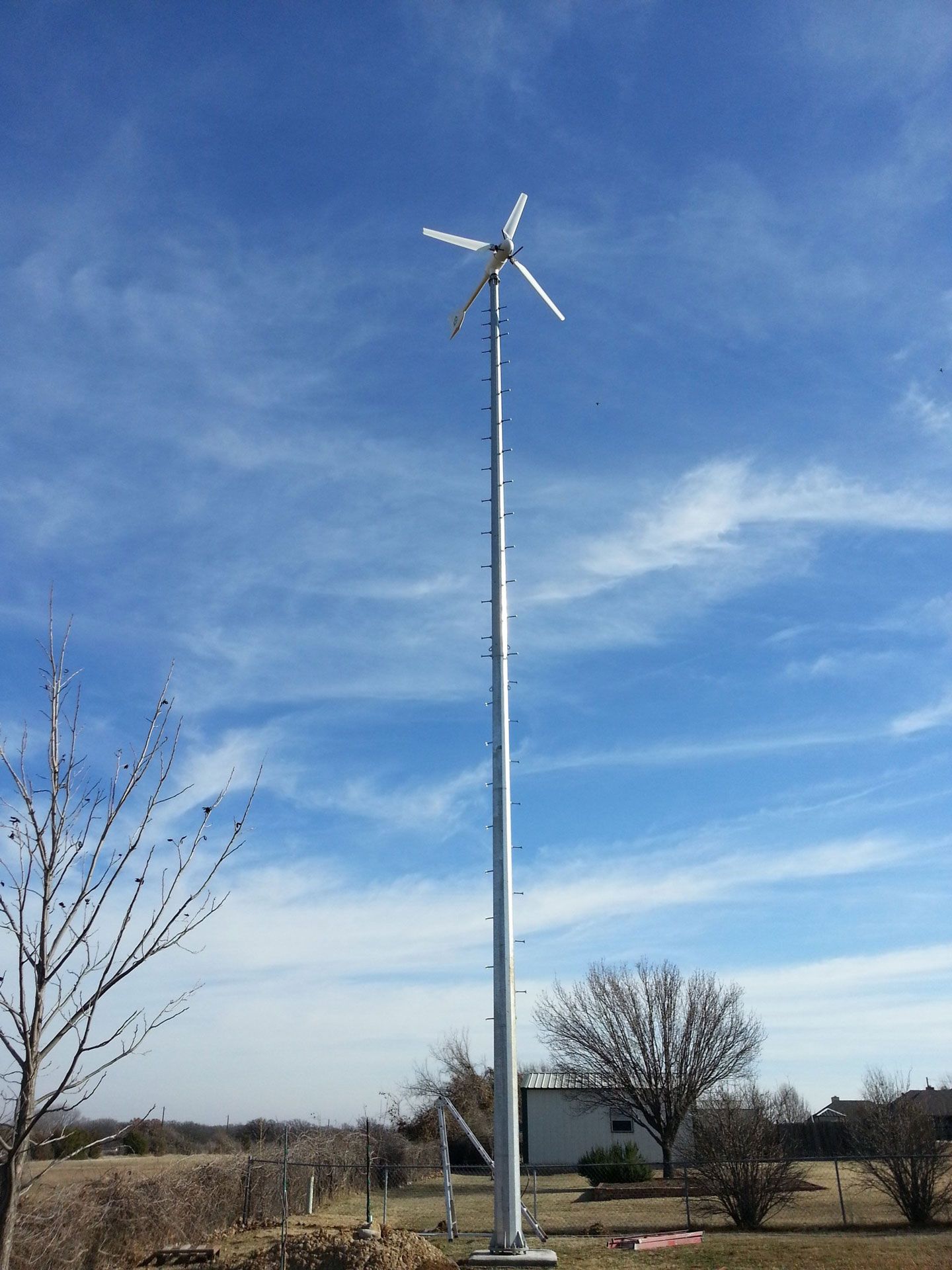A wind turbine on a pole with a blue sky in the background