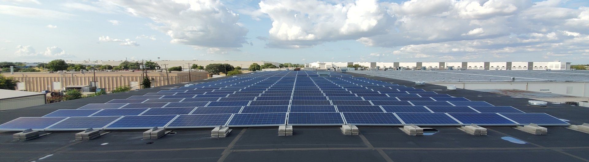 There are many solar panels on the roof of a building.