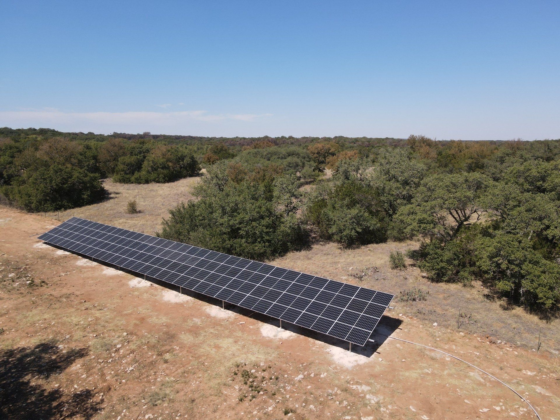 A row of solar panels sitting on top of a dirt field.