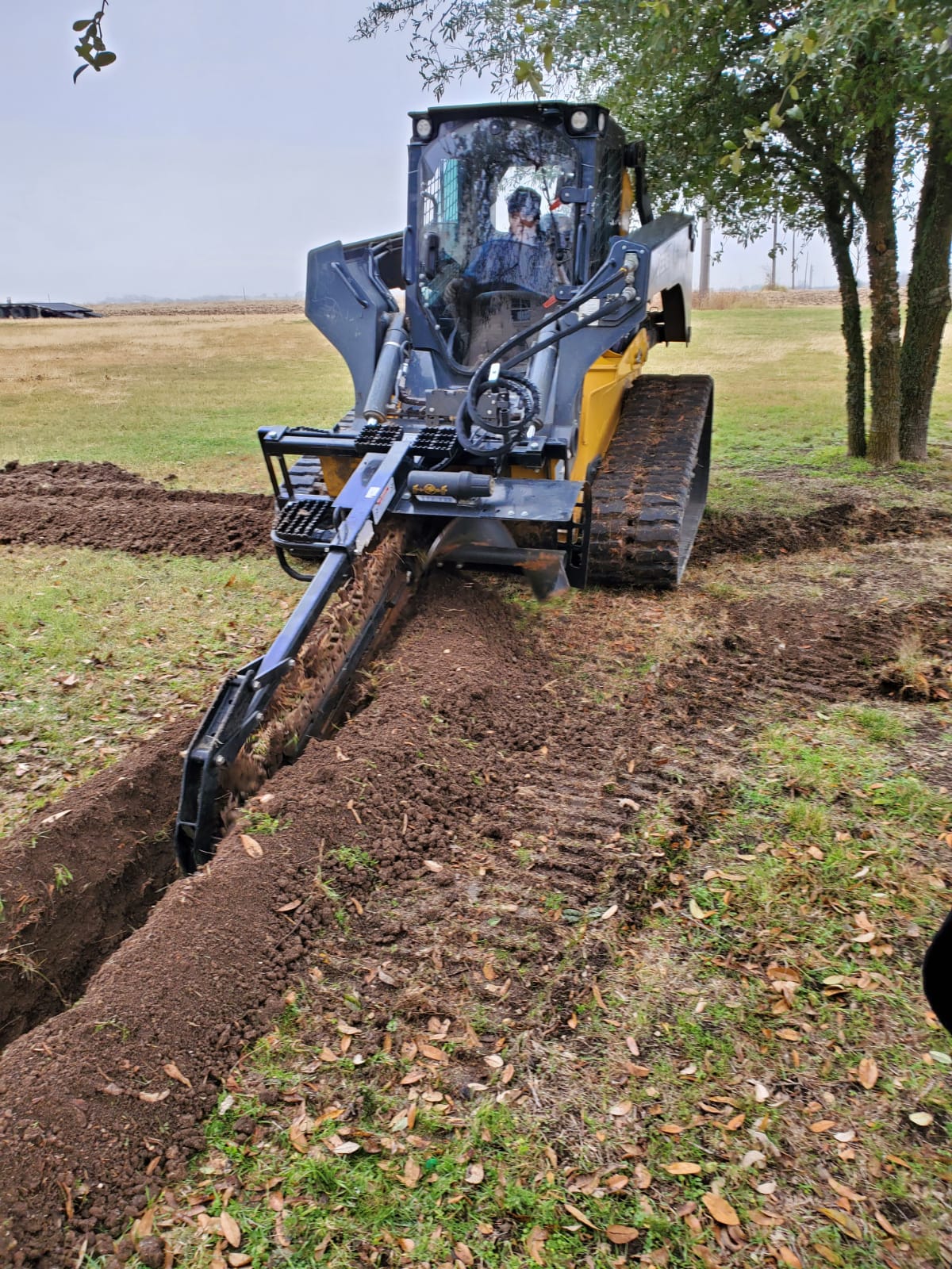 A bulldozer is digging a trench in a field.