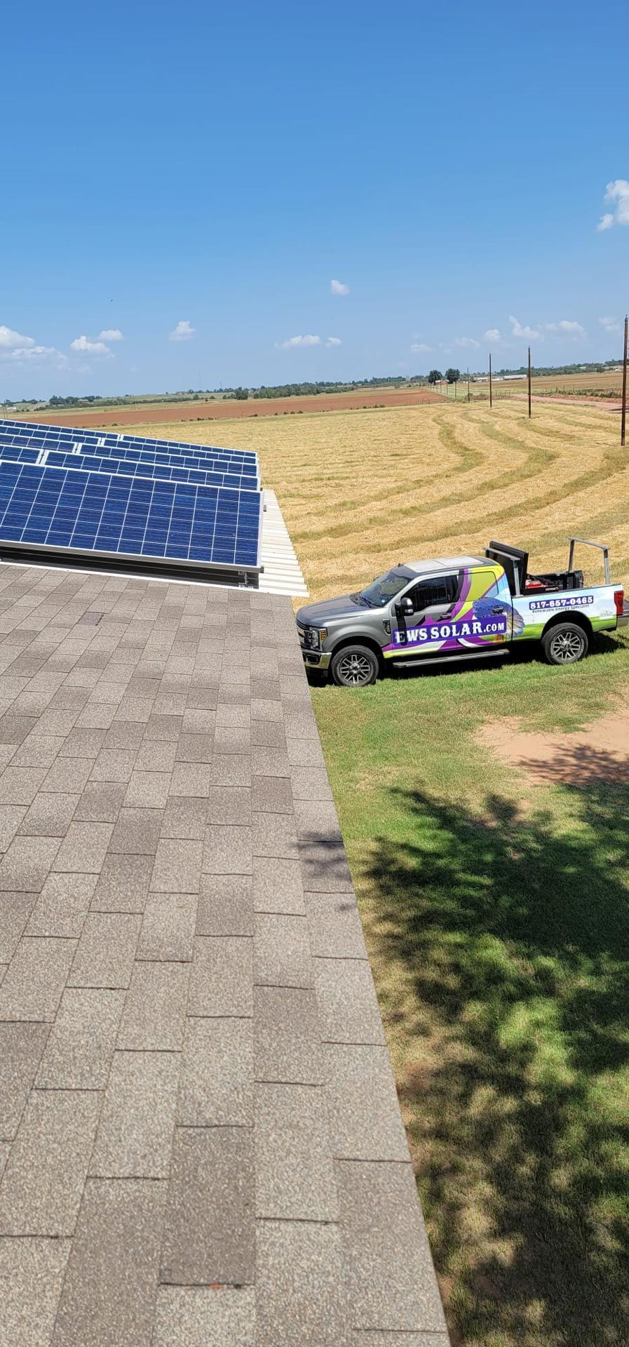 A truck is parked on a roof next to a field of solar panels.