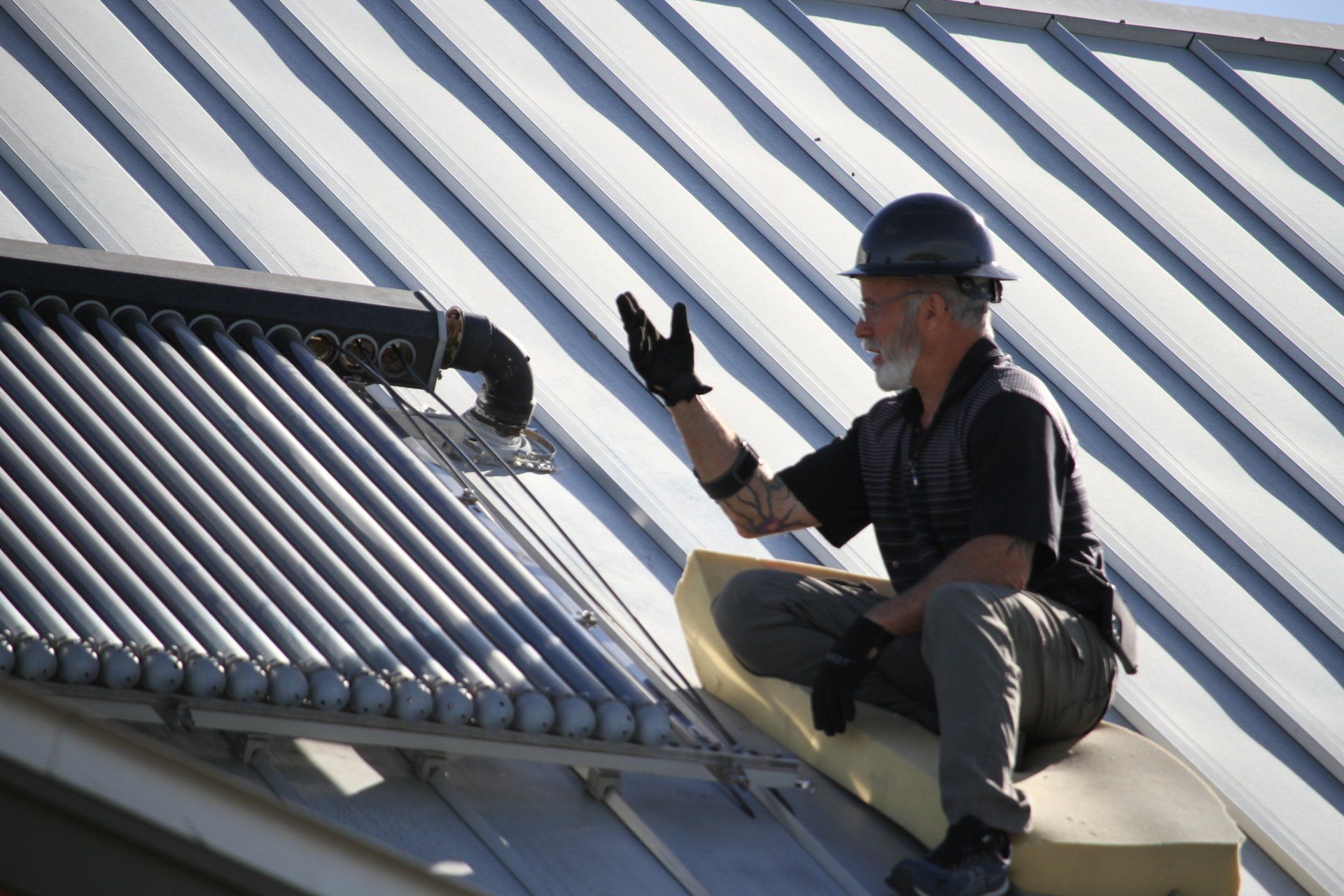 A man wearing a hard hat is sitting on the roof of a building