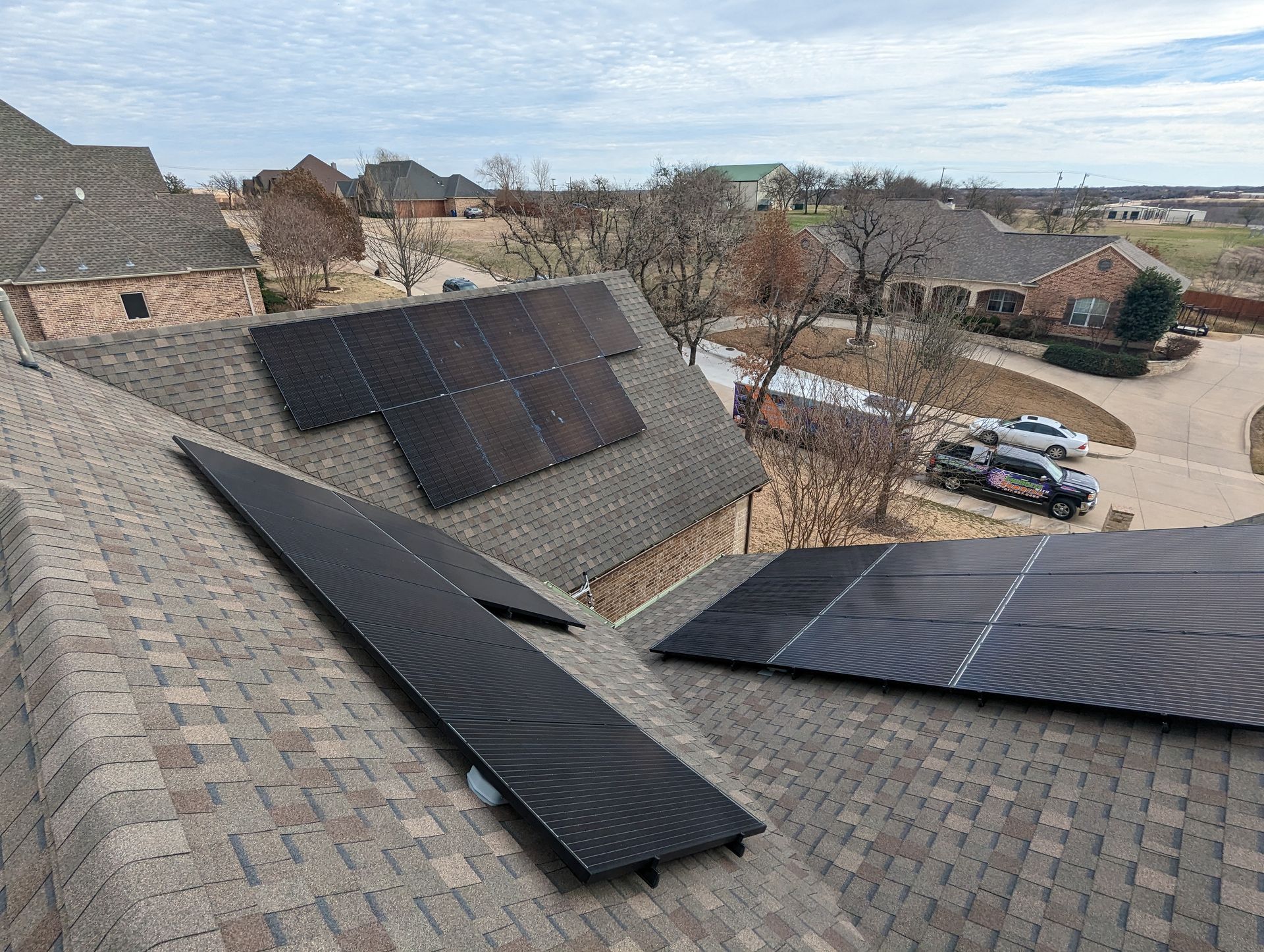 There are many solar panels on the roof of a house.