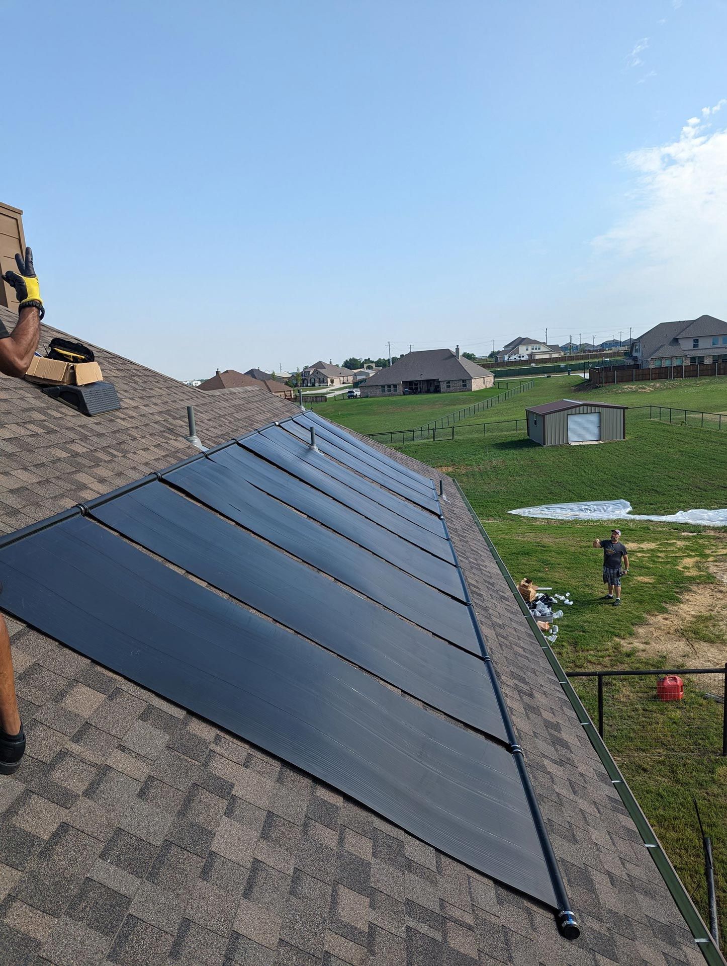 A man is installing solar panels on the roof of a house.