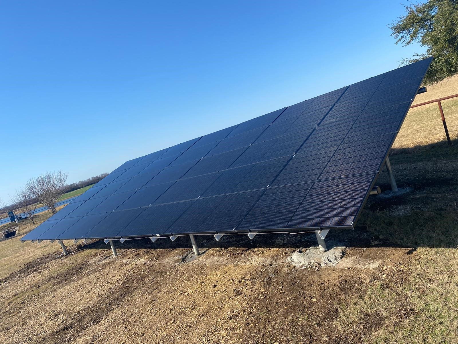 A large solar panel is sitting on top of a dirt field.
