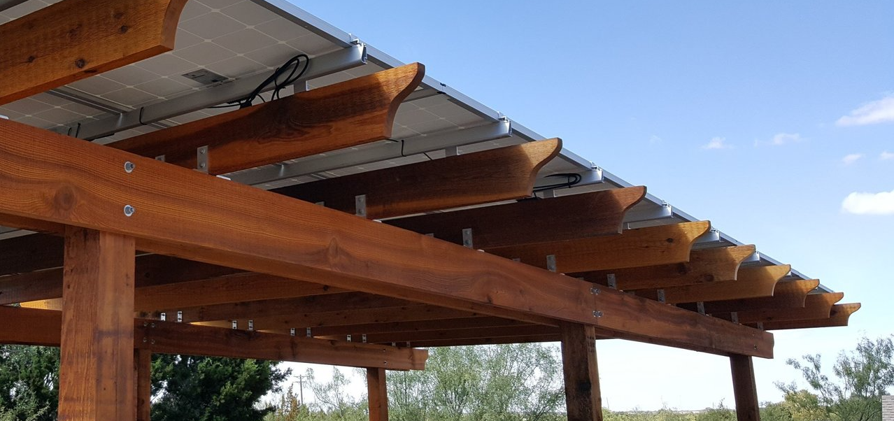 A wooden pergola with solar panels on the roof.