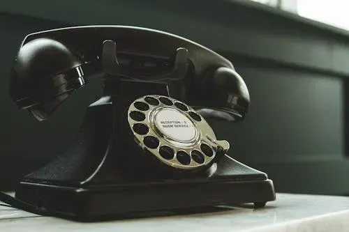 An old black telephone is sitting on a white table.