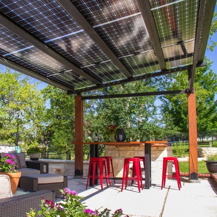 A patio with a pergola covered in solar panels and red stools.