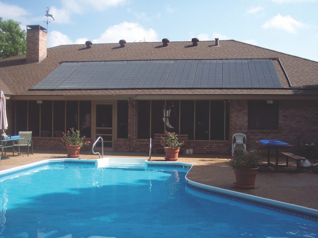 A swimming pool in front of a house with solar panels on the roof