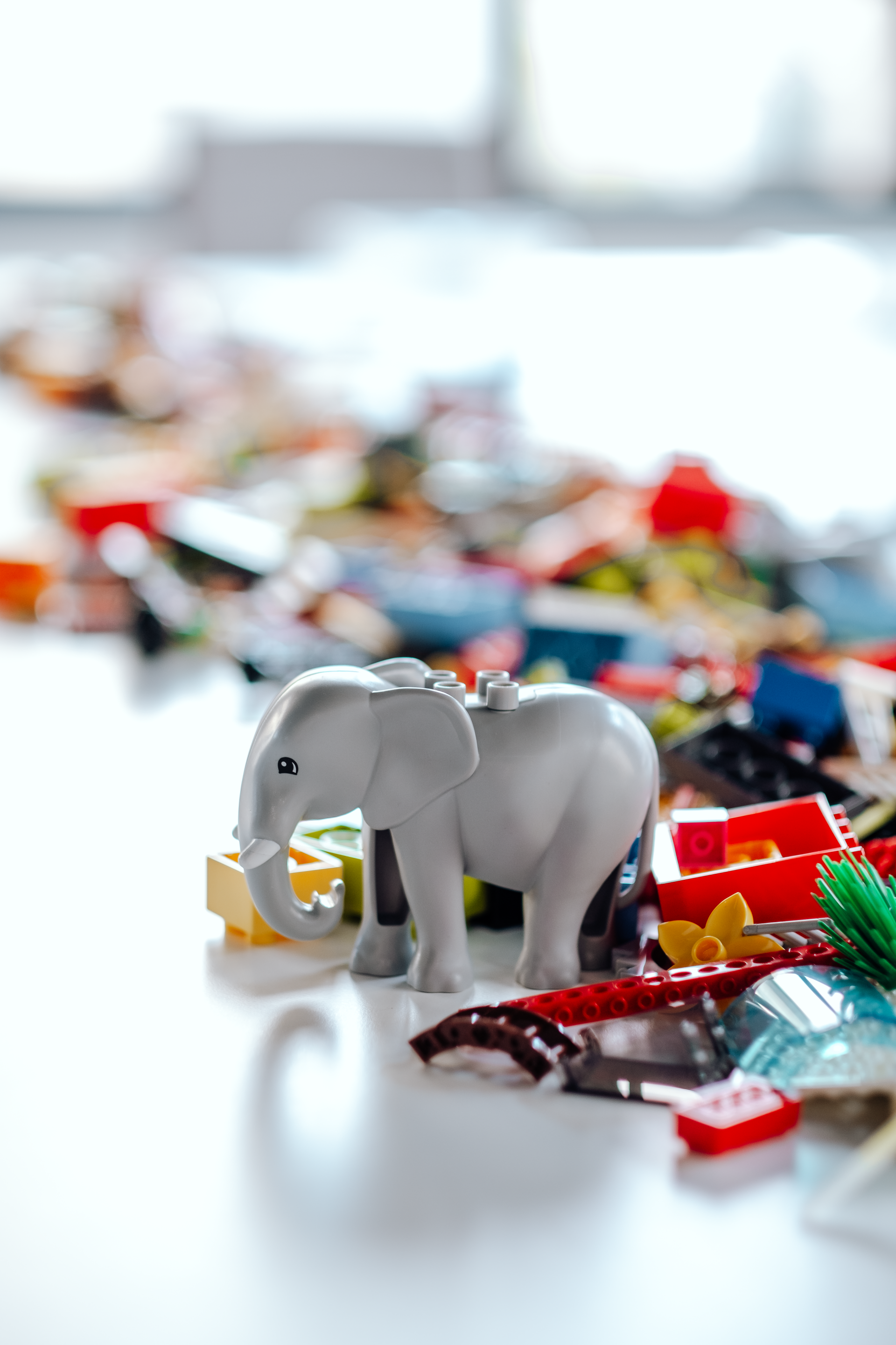 A toy elephant is sitting on a table next to a pile of lego blocks.