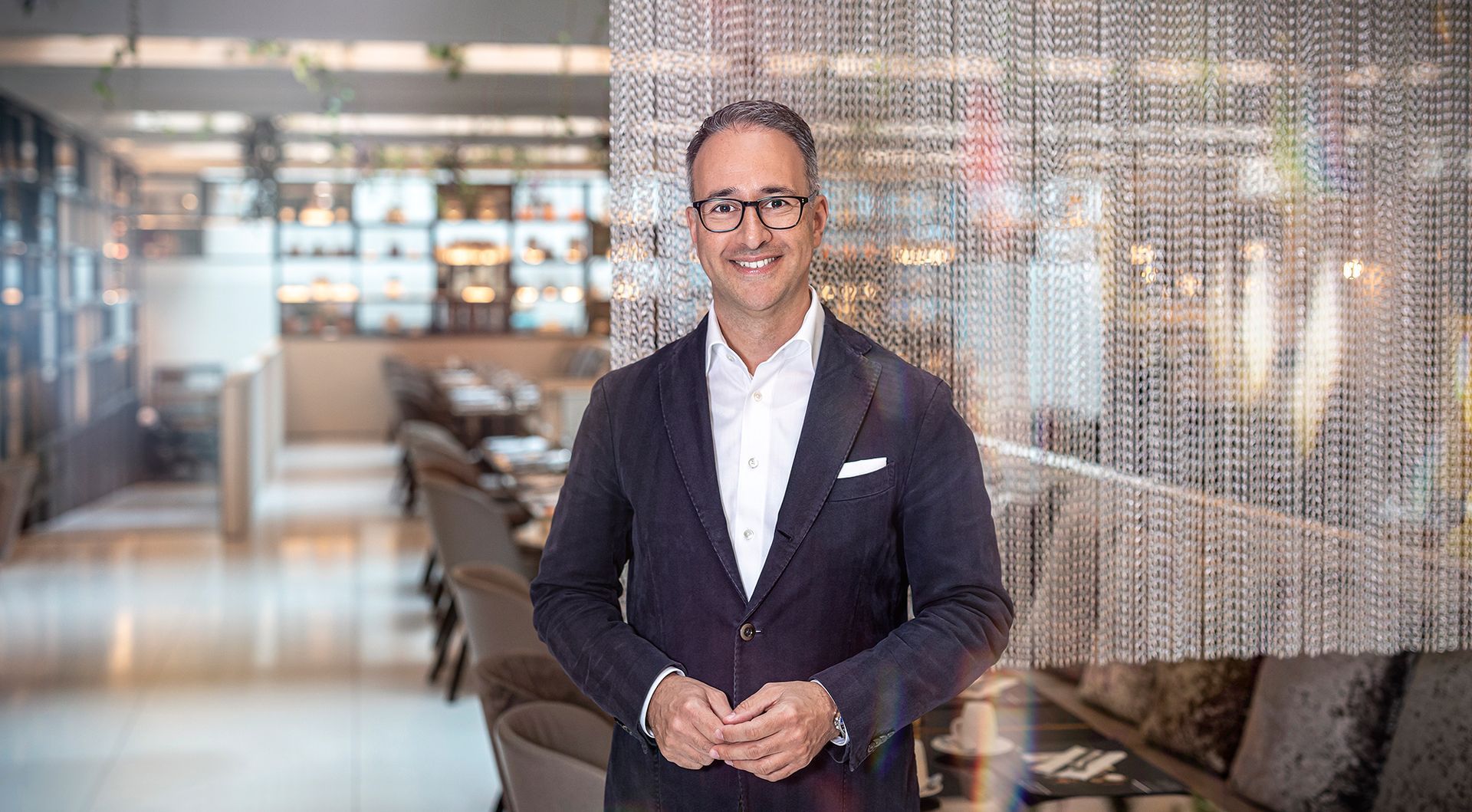 A man in a suit and glasses is standing in a restaurant.