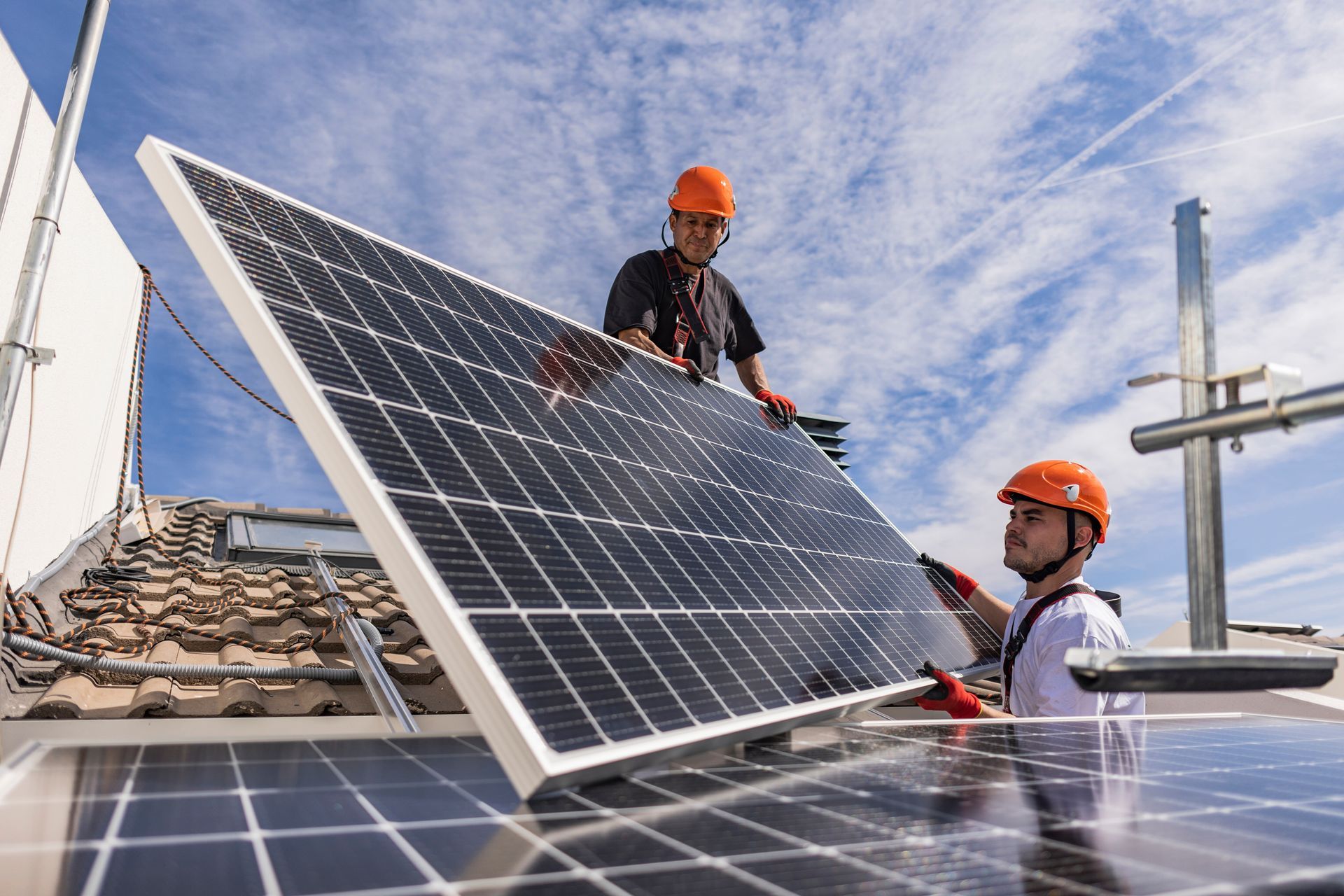 Two engineers wearing hard hats together installing solar panels. Two engineers wearing hard hats together installing solar panels.