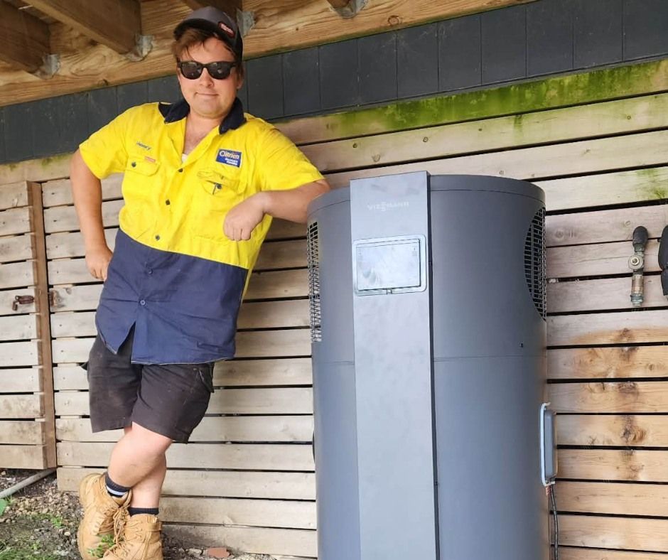 A plumbing professional adjusting the control panel on a hot water system.