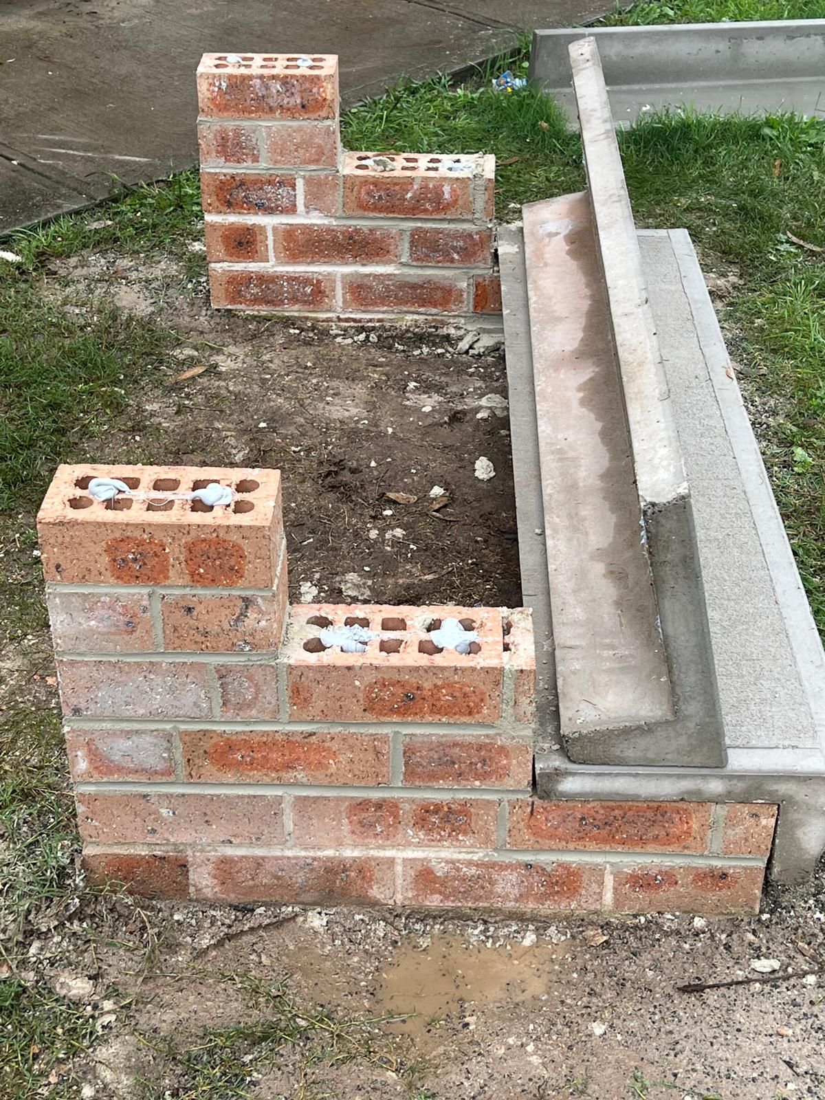 A brick wall is being built in a yard.