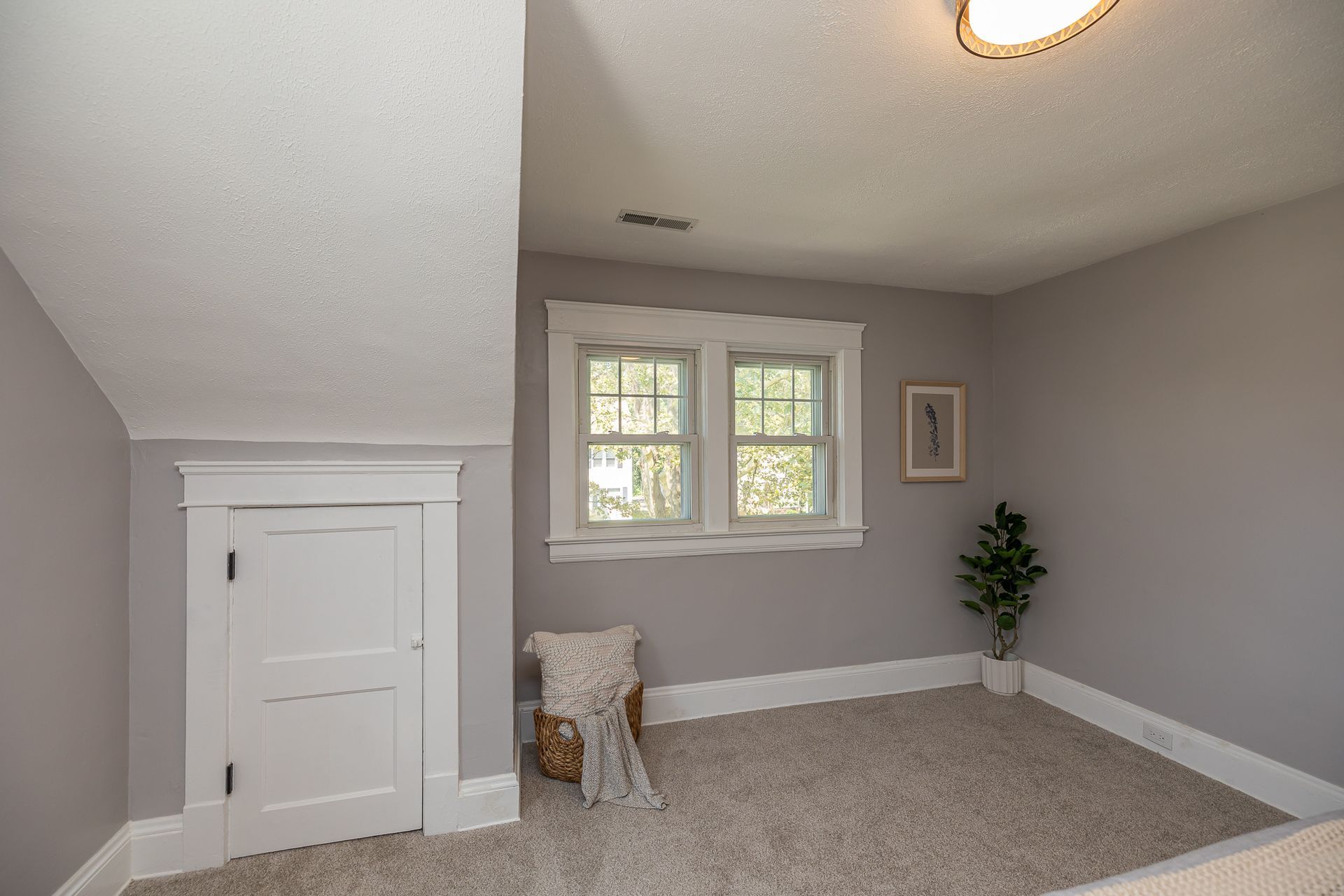 Small room with a window, white trim, gray walls, carpet, and a white door.