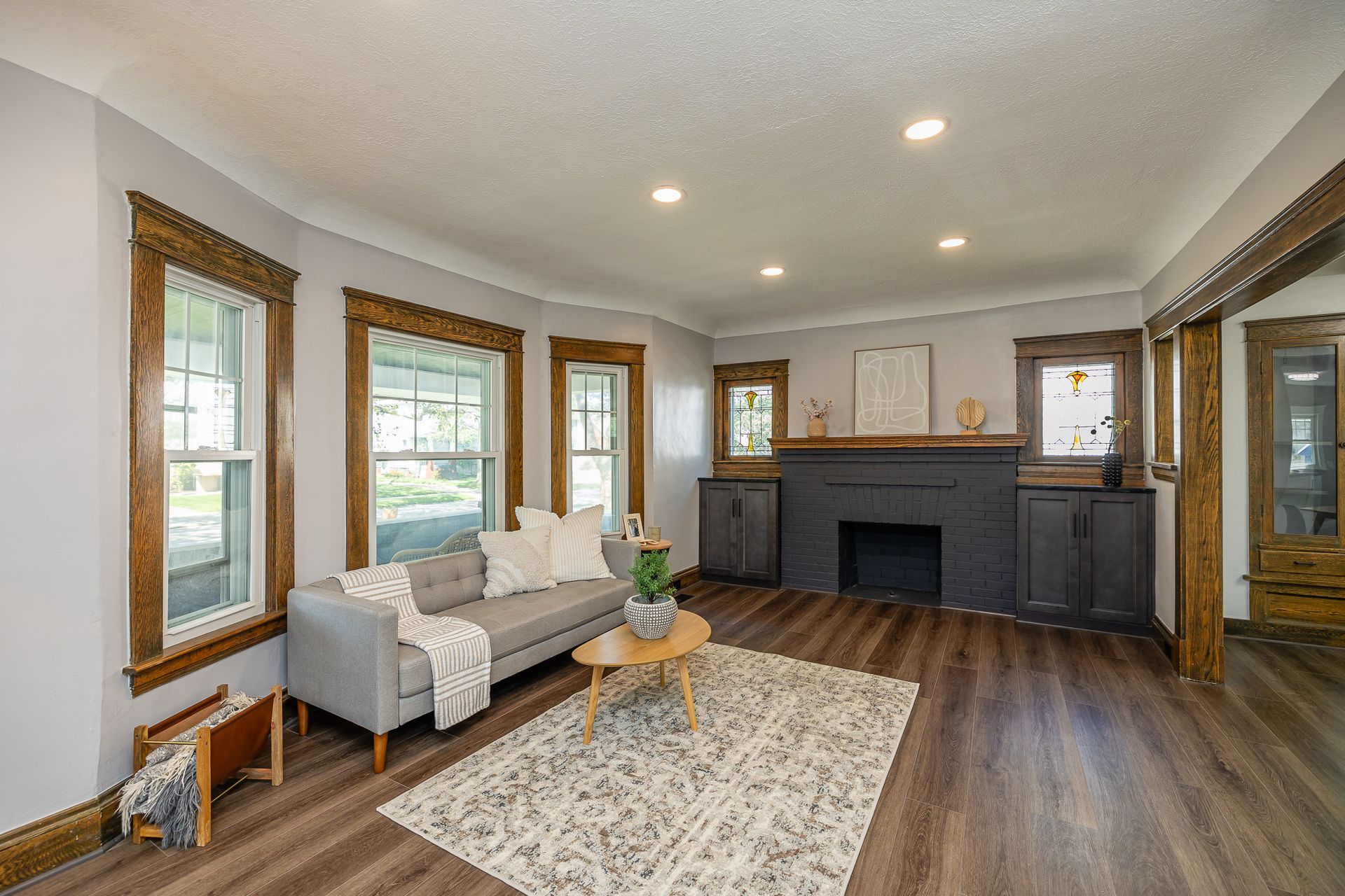 Living room with gray couch, fireplace, hardwood floors, and patterned rug.