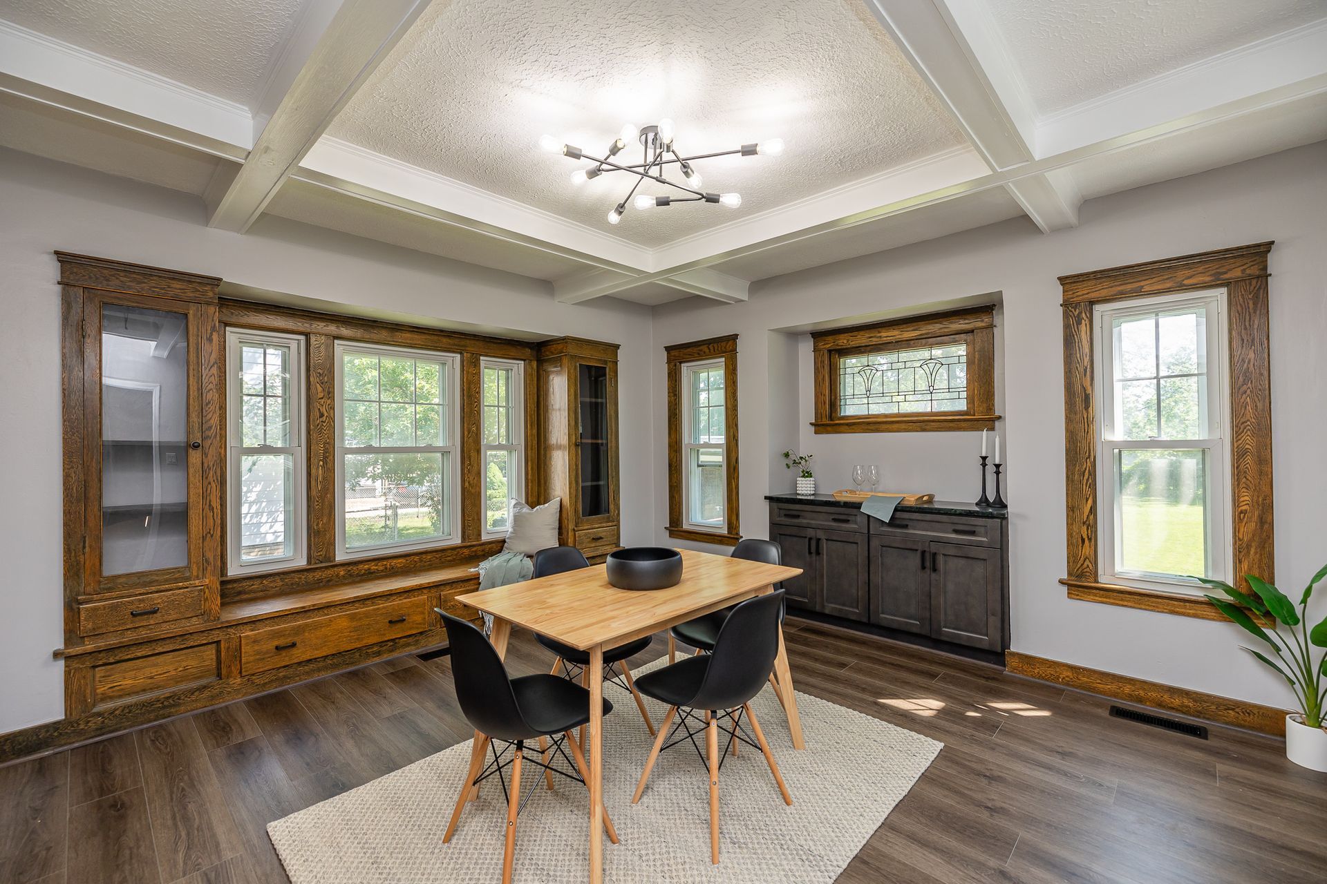 Dining room with dark wood trim, gray walls, modern table and chairs, and a light fixture.
