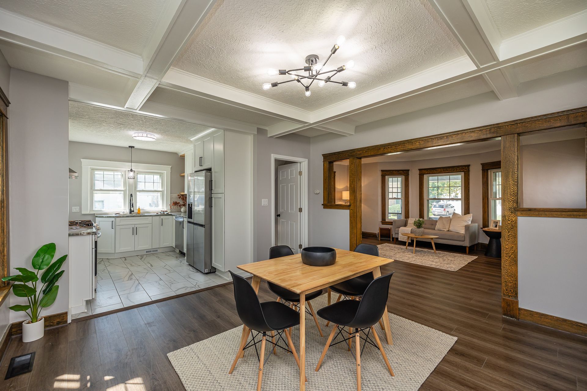 Open-concept dining room with table, chairs, and view into kitchen and living room; light and dark wood accents.