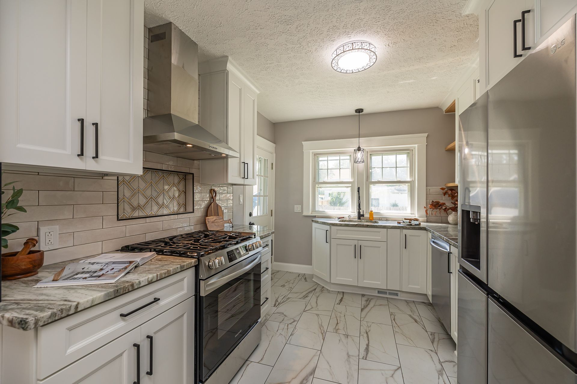 White kitchen with stainless steel appliances, white cabinets, and light gray countertops.