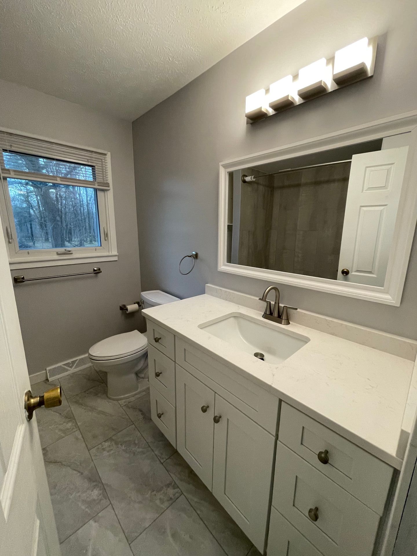 Bathroom with white vanity, gray walls, and a window.