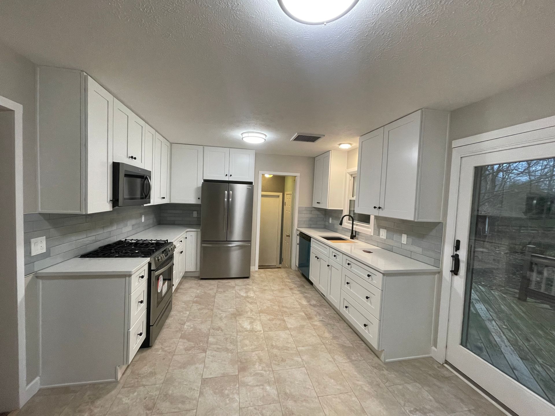 Modern kitchen with white cabinets, stainless steel appliances, and a gray backsplash.