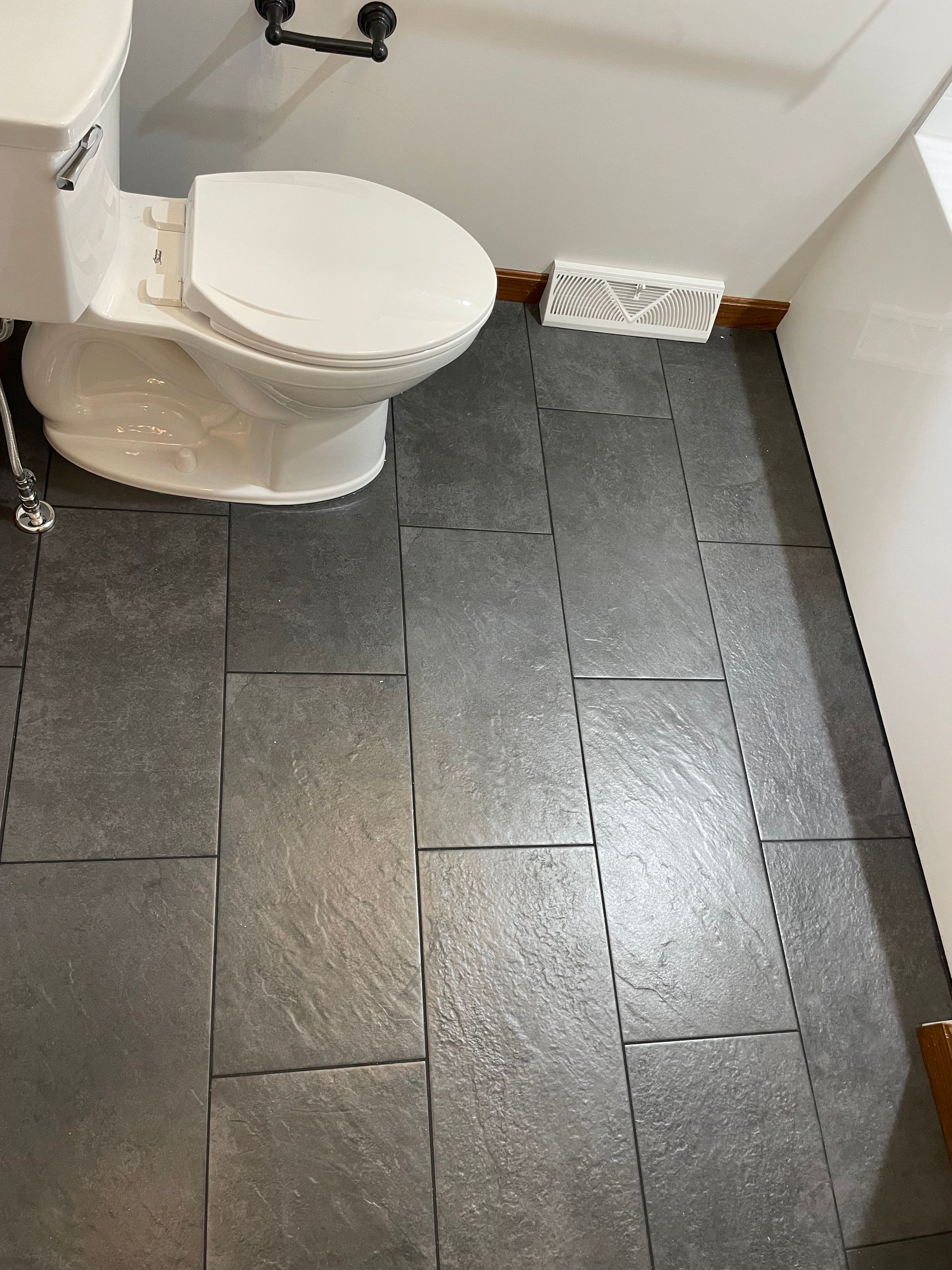 Bathroom with a white toilet and dark gray tiled floor.
