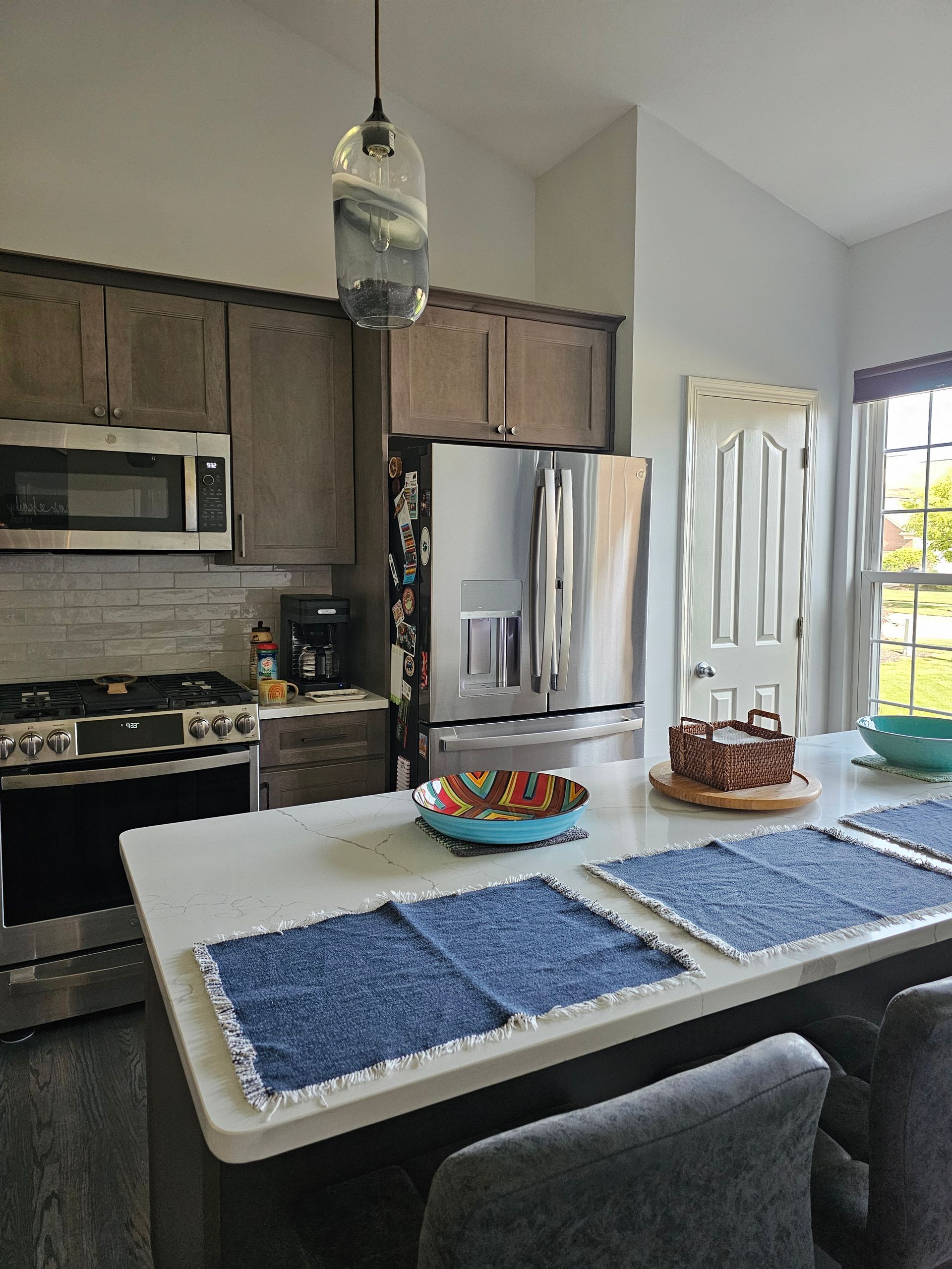 Kitchen with stainless steel appliances, island with blue placemats, and a repurposed door.