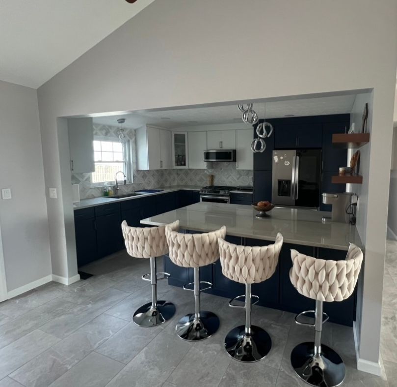 Kitchen with a large island and bar seating, two-tone cabinets (navy and white), and tiled flooring.