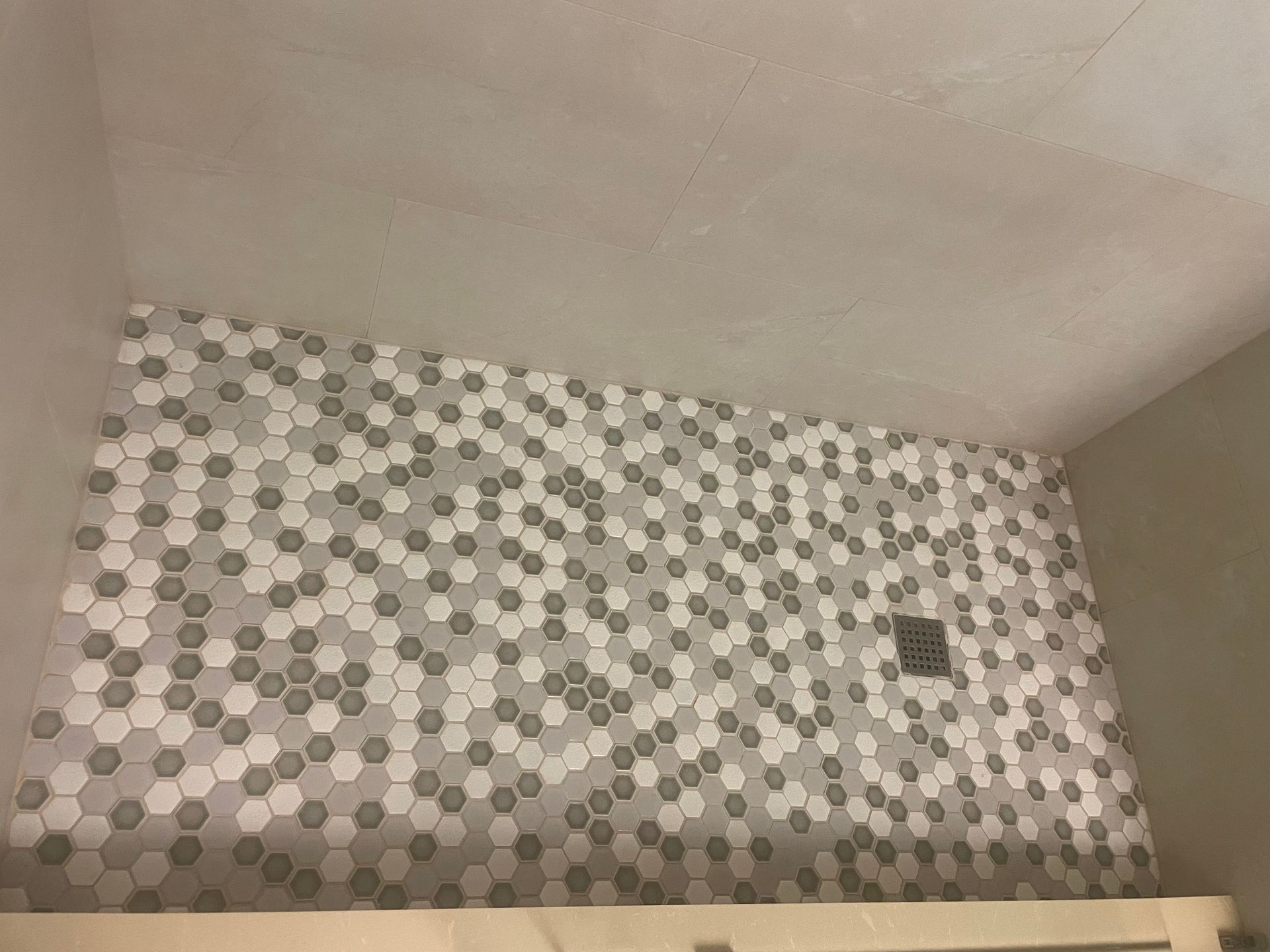 Bathroom wall with gray and white honeycomb tiles.
