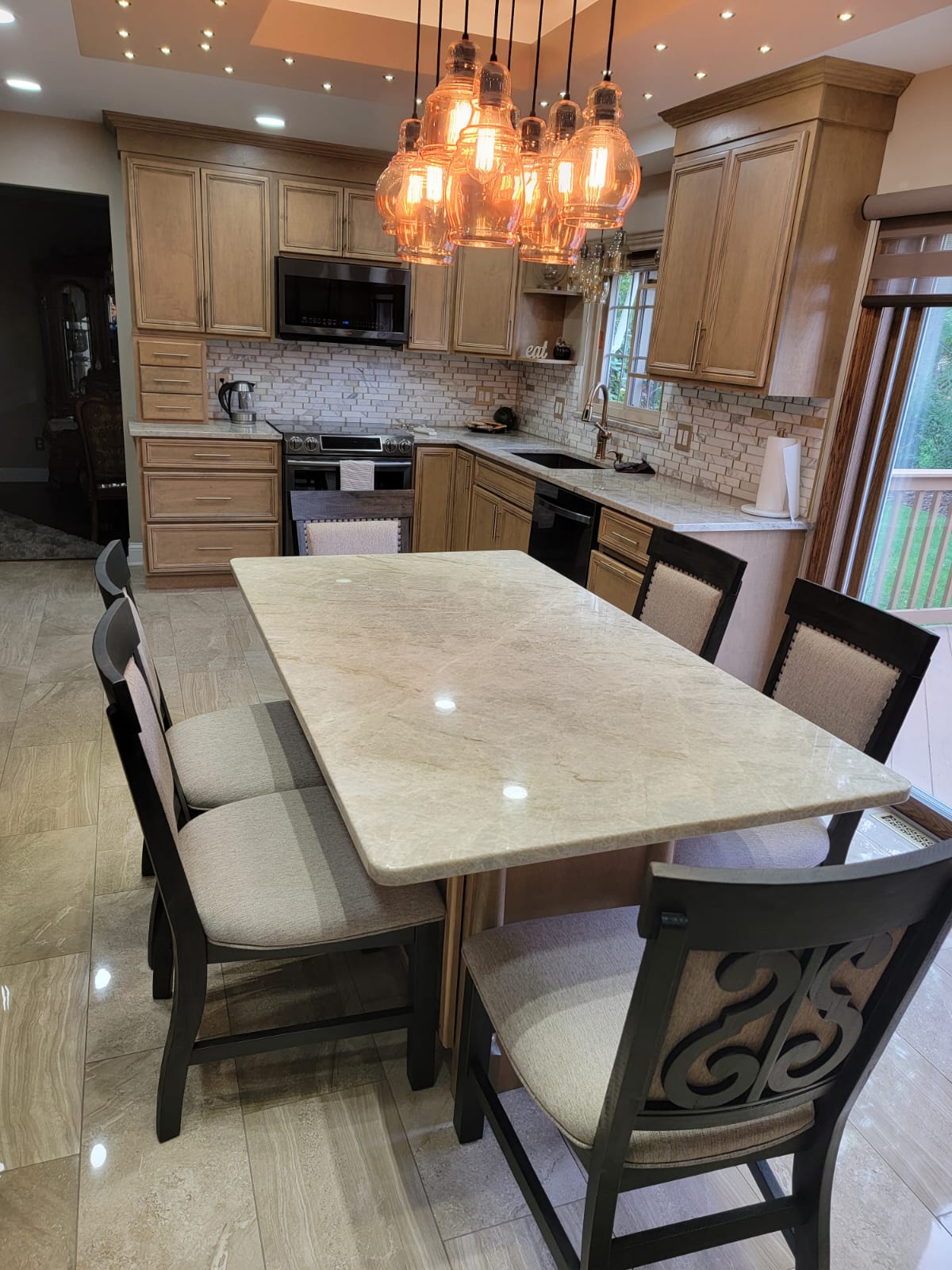 Kitchen with light wood cabinets, granite countertops, and a dining table with chairs.