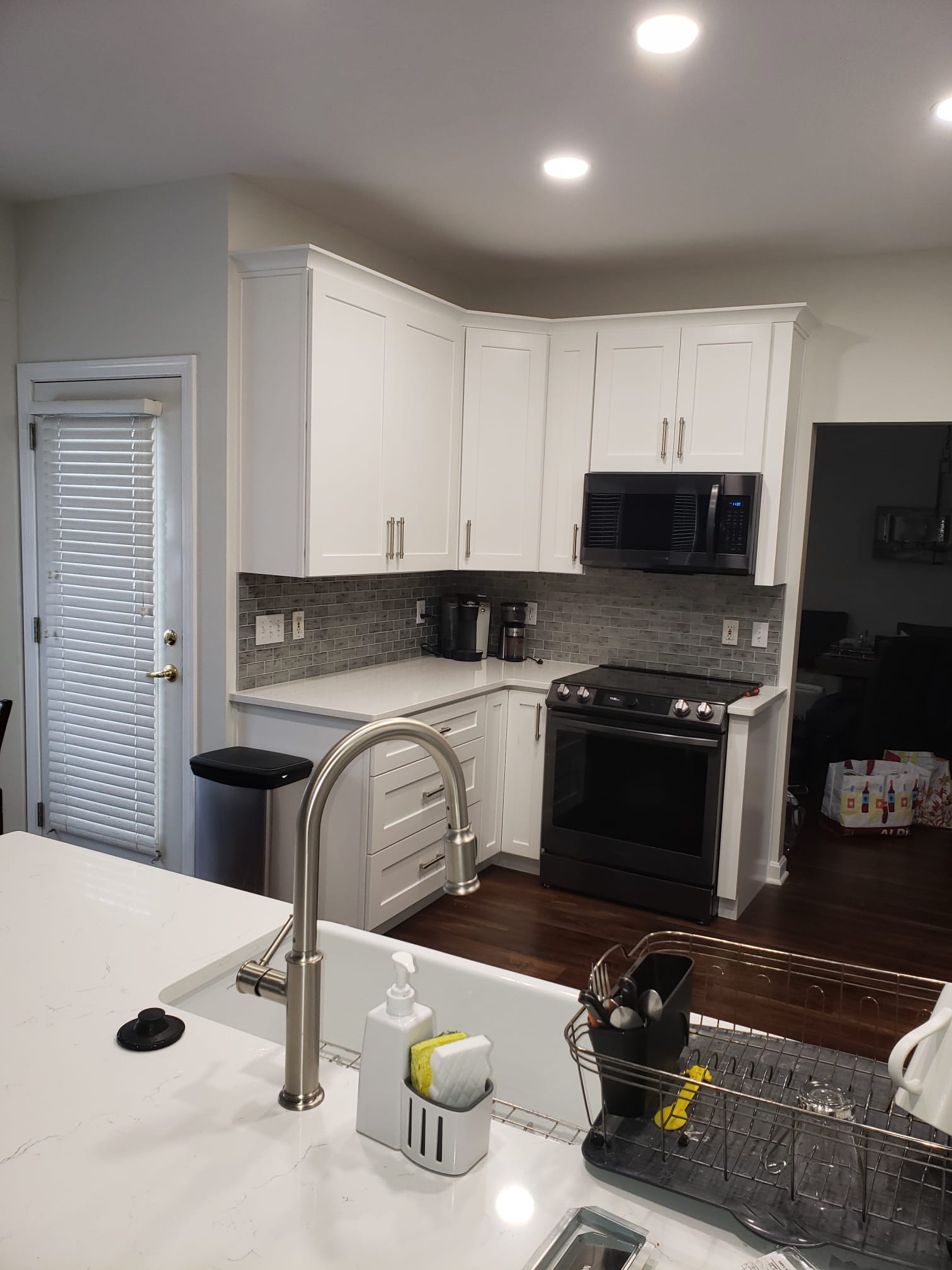 Modern kitchen with white cabinets, dark appliances, and a marble countertop.