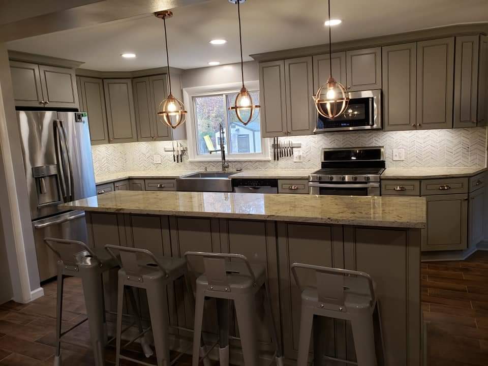 Gray kitchen with island, countertops, cabinets, and pendant lights. Stainless steel appliances.