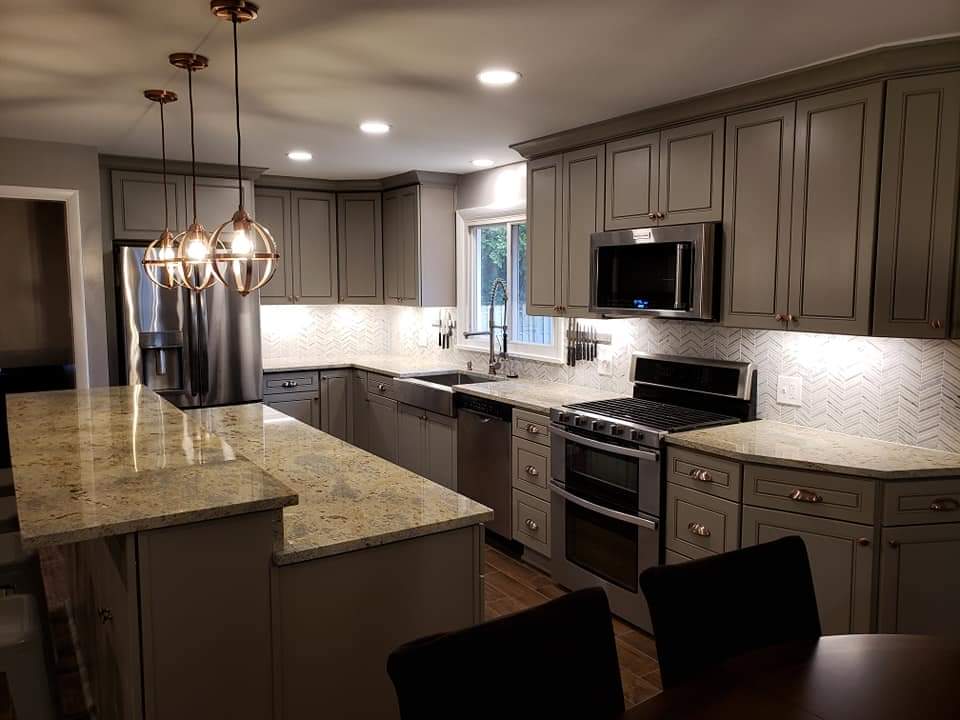 Modern kitchen with gray cabinets, stainless steel appliances, and granite countertops.