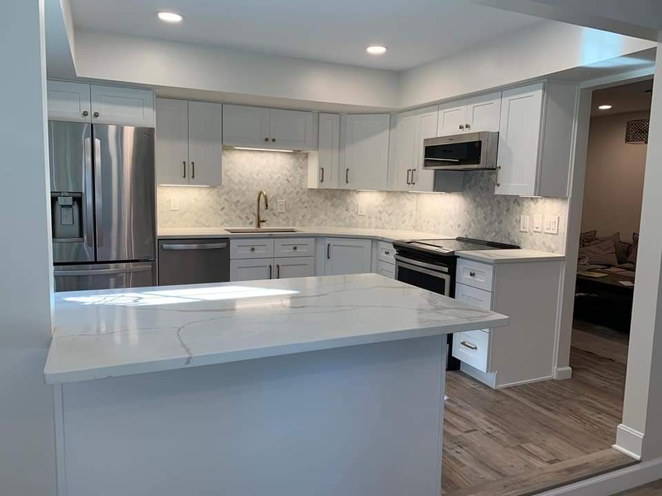 Modern white kitchen with stainless steel appliances and a white countertop island.