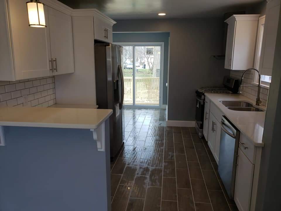 White kitchen with gray walls, stainless steel appliances, and a sliding glass door.