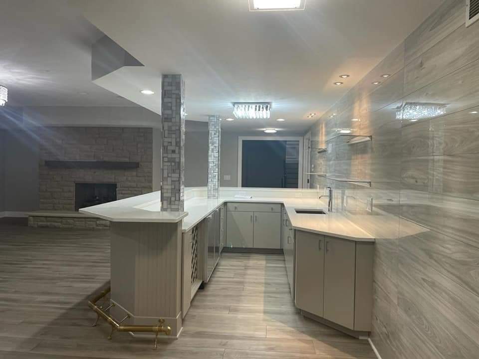 Finished basement with bar. Light gray cabinets, white countertops, and stone-look tile walls.