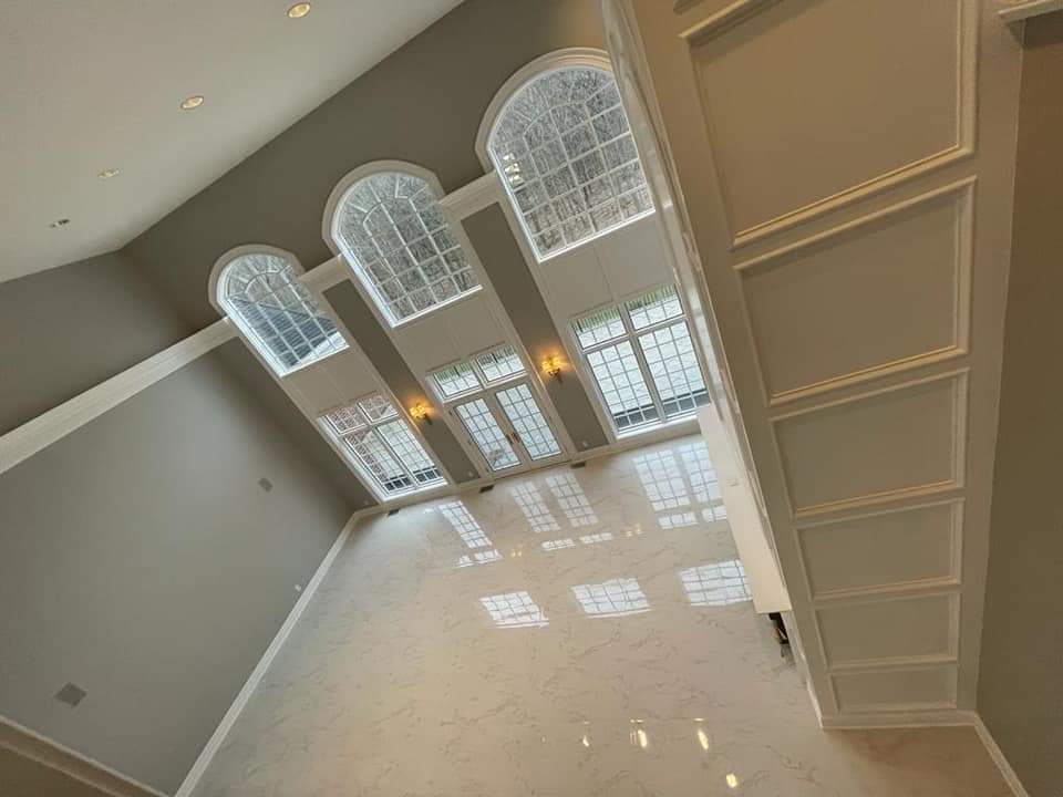 High-angle view of a room with large arched windows and a glossy floor; neutral colors and architectural details.
