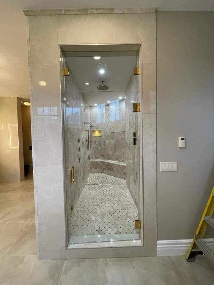 Walk-in shower with gold hardware, marble tile, and a built-in bench.
