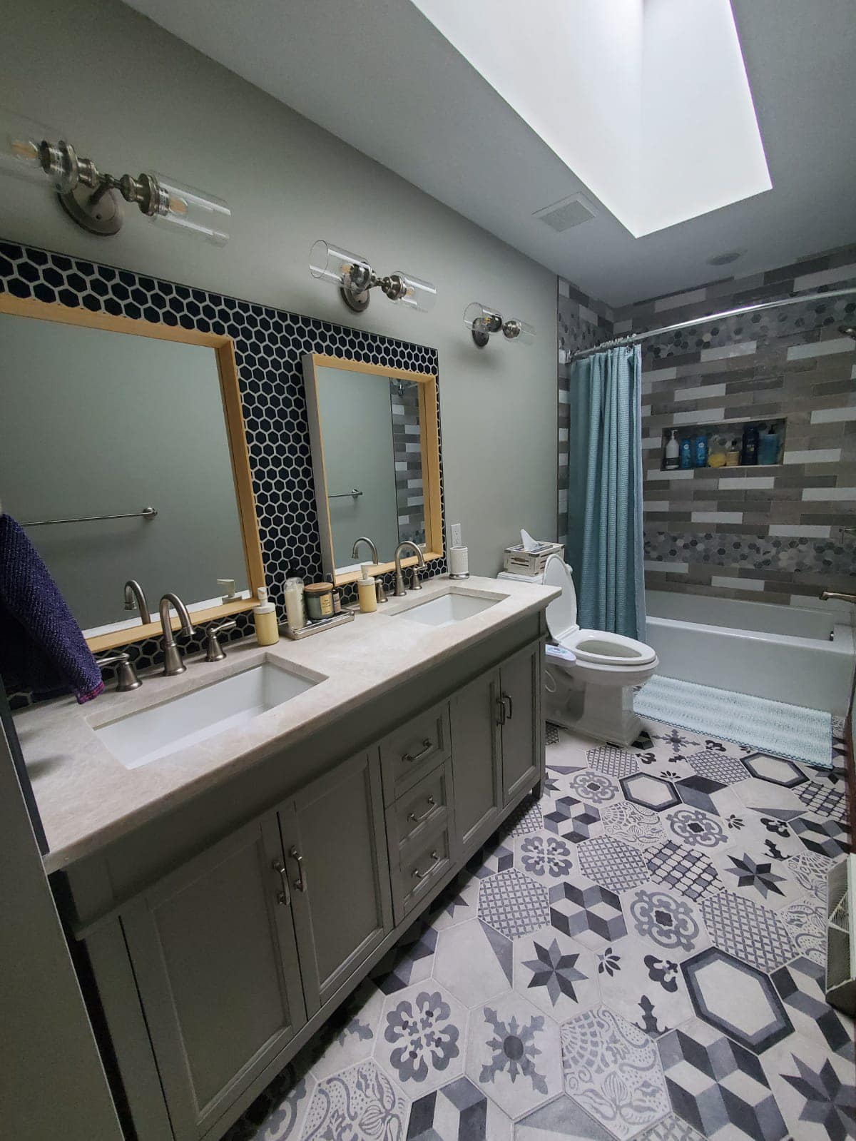 Bathroom with patterned floor, double sinks, and a shower with a blue curtain.