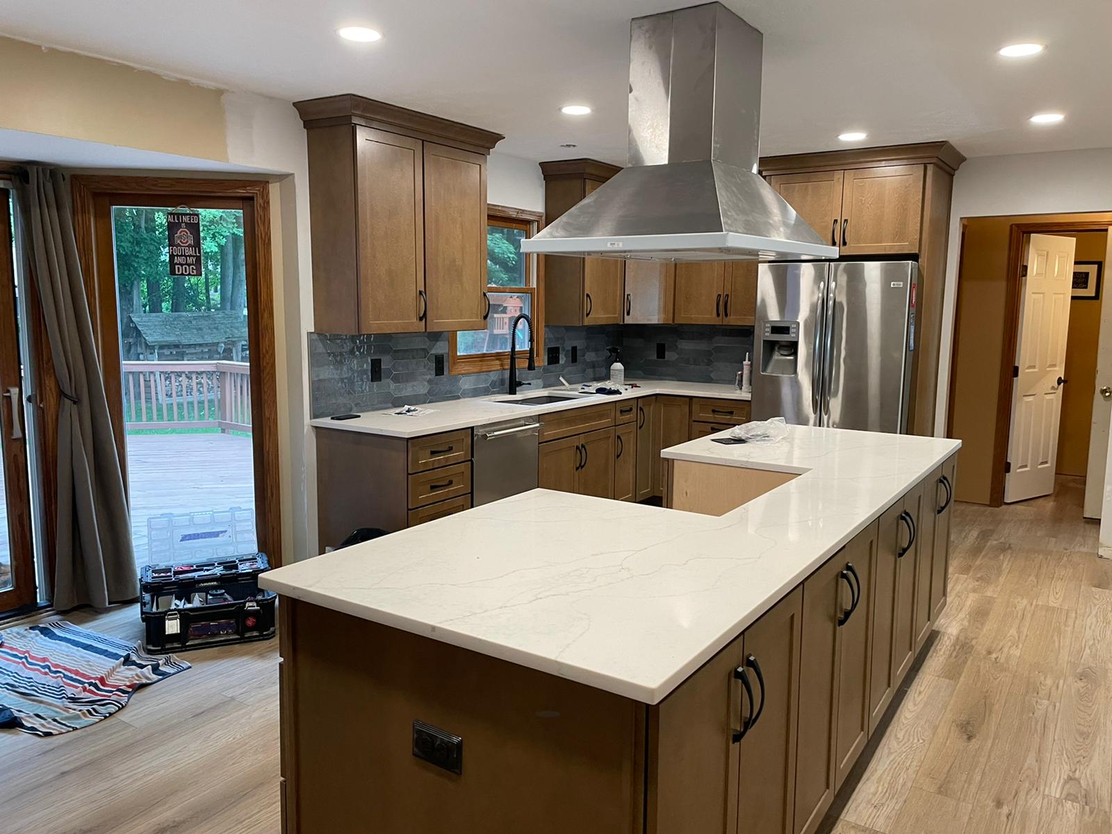 Kitchen with wooden cabinets, stainless steel appliances, and a large island with white countertop.