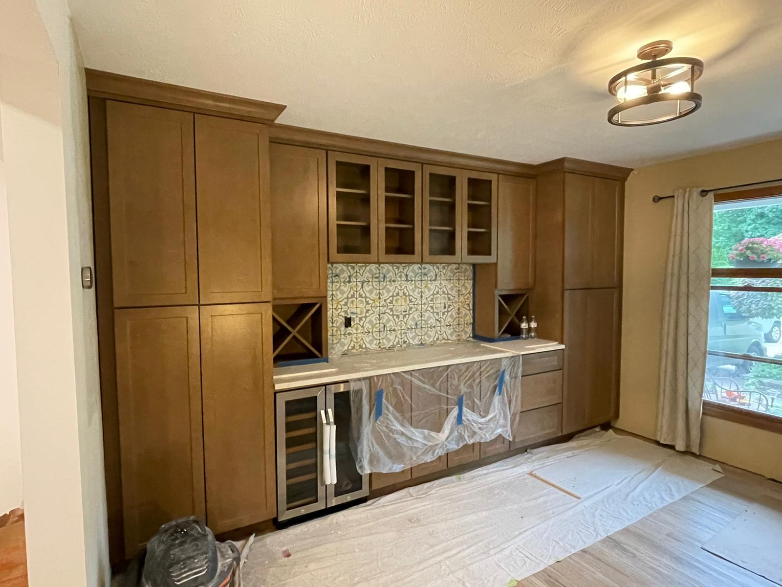 Built-in brown cabinets with wine storage, a bar area, and a mini-fridge in a room with a window.