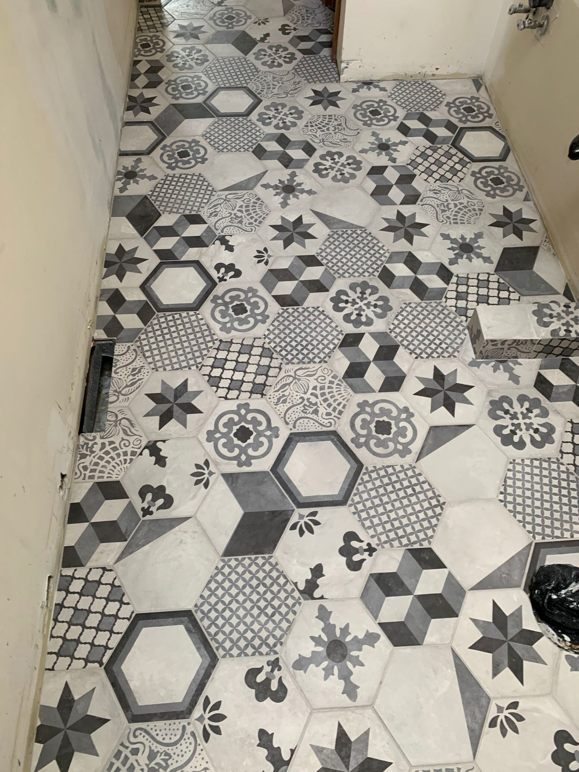Hexagonal patterned tiles in shades of gray and white cover a floor.