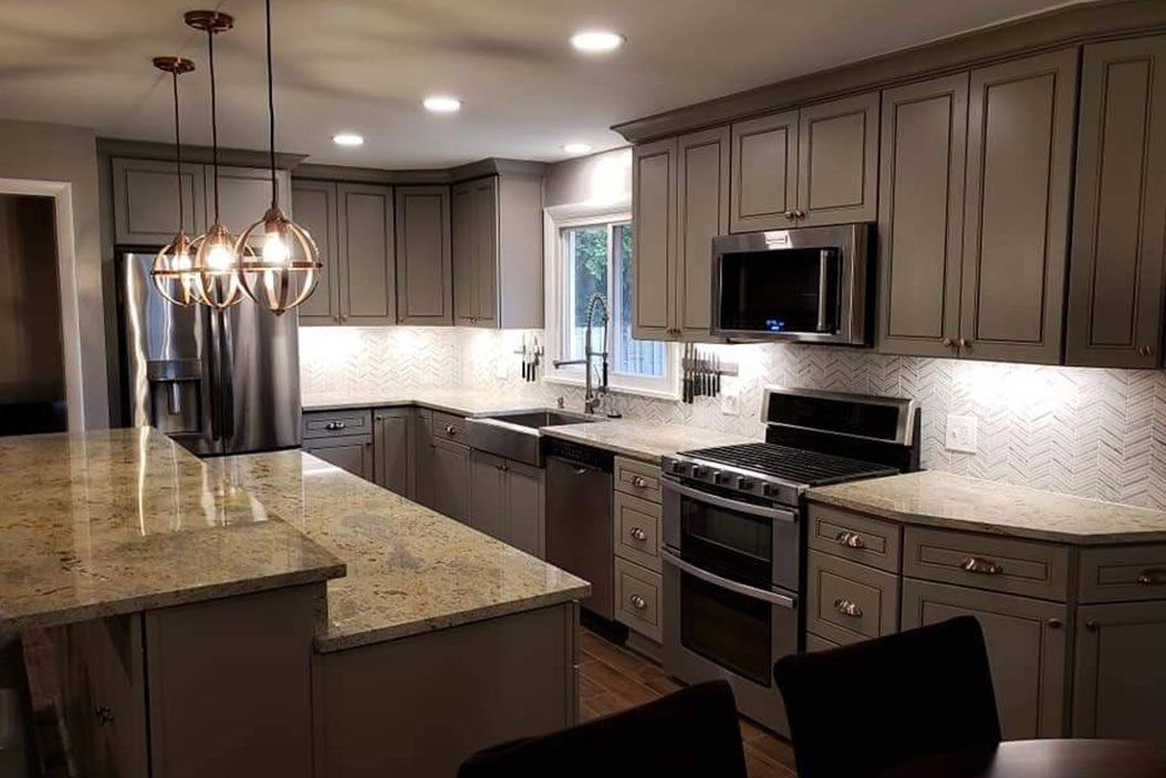 Gray kitchen with stainless steel appliances, granite countertops, and pendant lights.