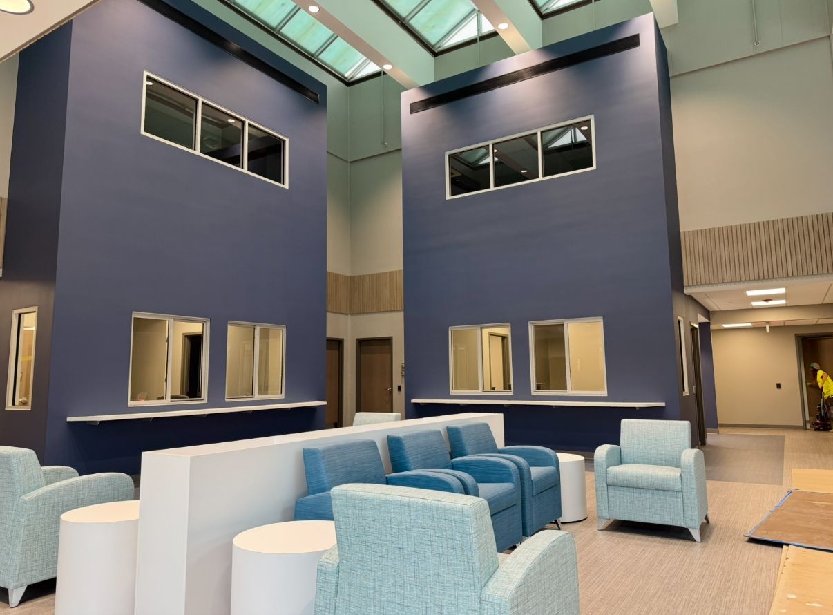 Waiting area with blue walls, blue armchairs, and a high ceiling.