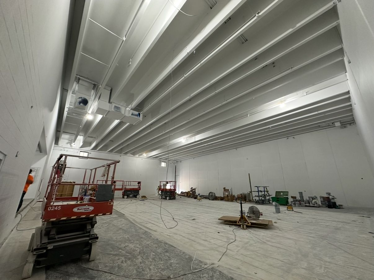 White interior with construction equipment; workers are in process of building.