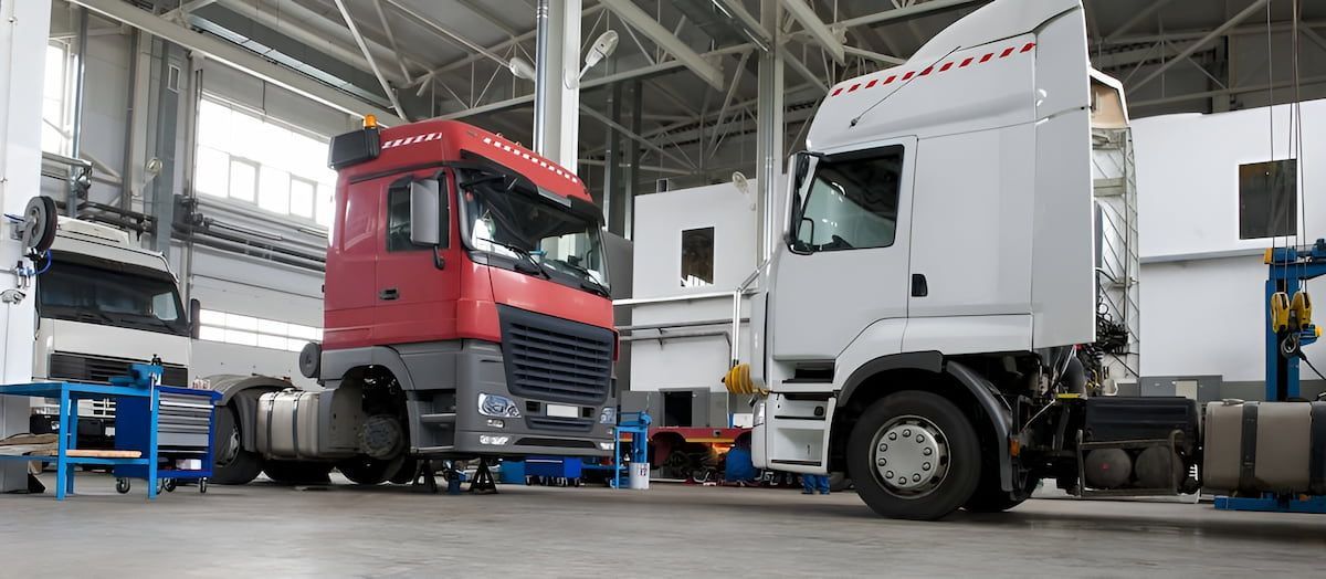 Two Semi Trucks Inside a Warehouse Garage, One Red and One White — Dentmaster Refinishing In Bungalow, QLD
