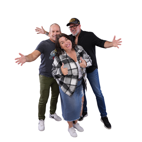 Four people standing together. One gives a thumbs-up, another points to their shirt. All are smiling.