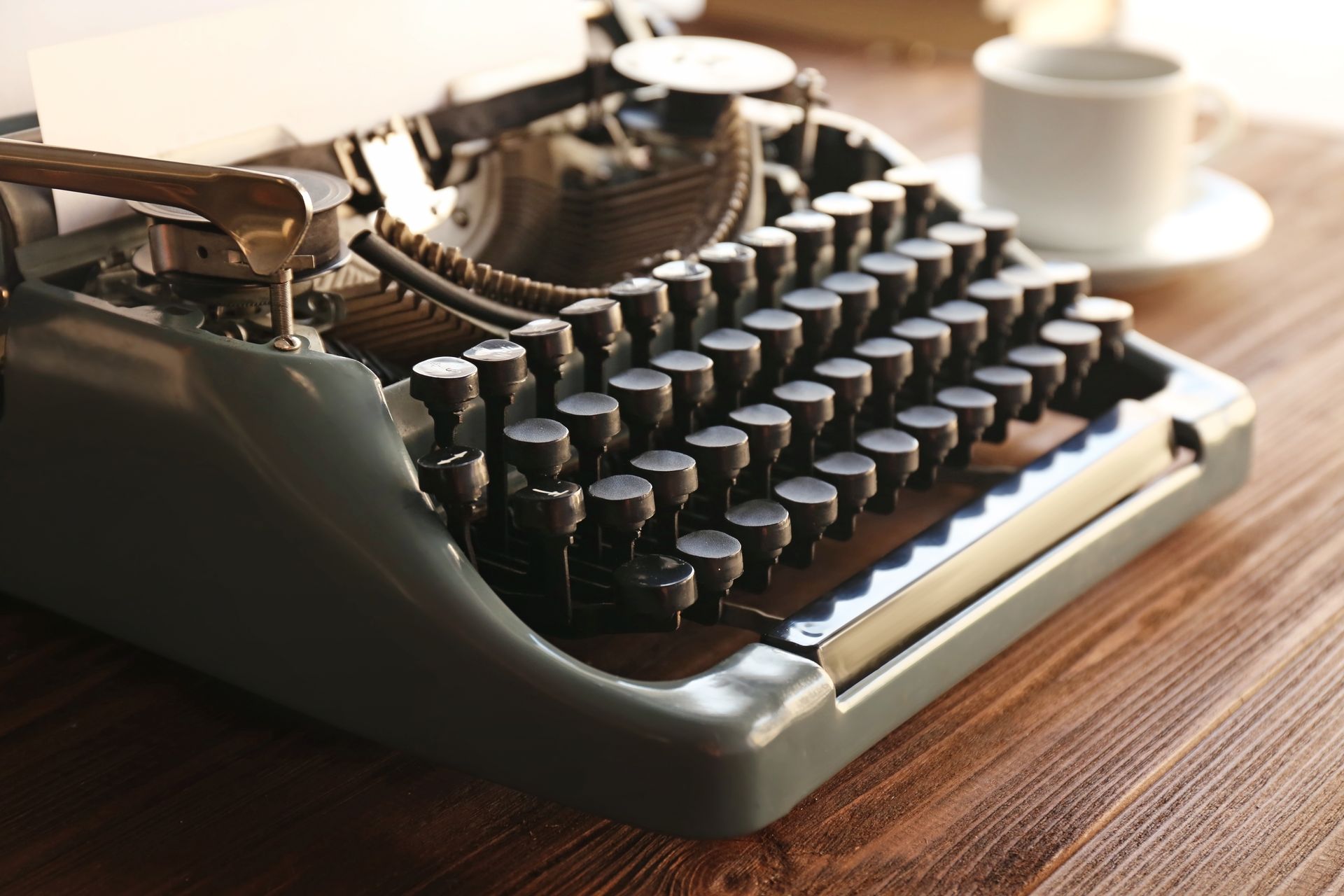 Vintage typewriter on a wooden desk with a coffee cup in the background