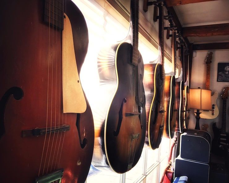Several acoustic guitars hanging on a wall in a room.