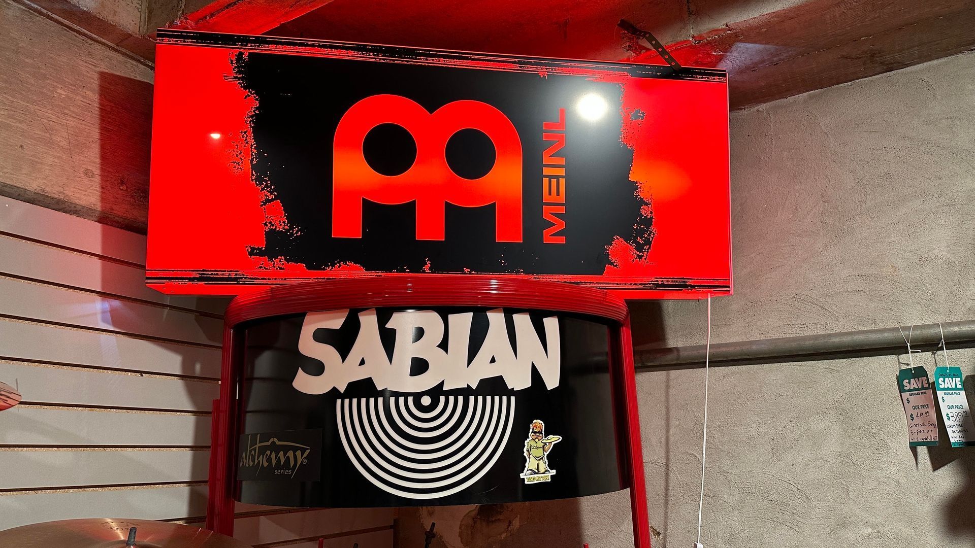 Red Meinl sign above a Sabian cymbal display in a store.